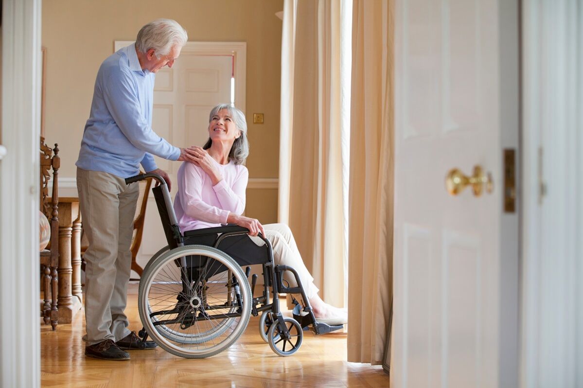 Woman in a wheelchair being pushed by her husband