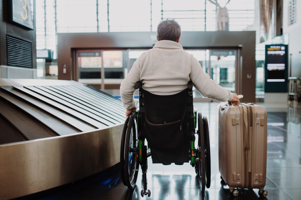 Person in a wheelchair in an airport with a suitcase