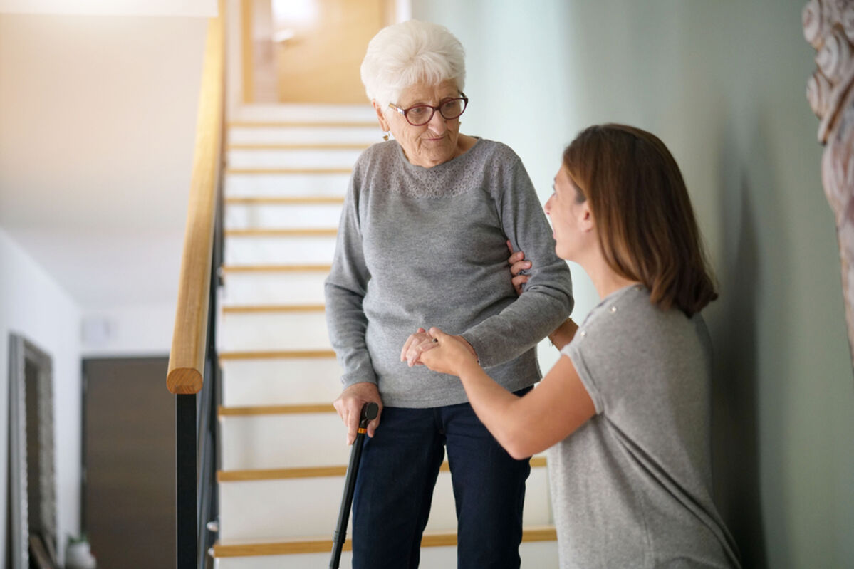 Carer helping elderly woman going down the stairs