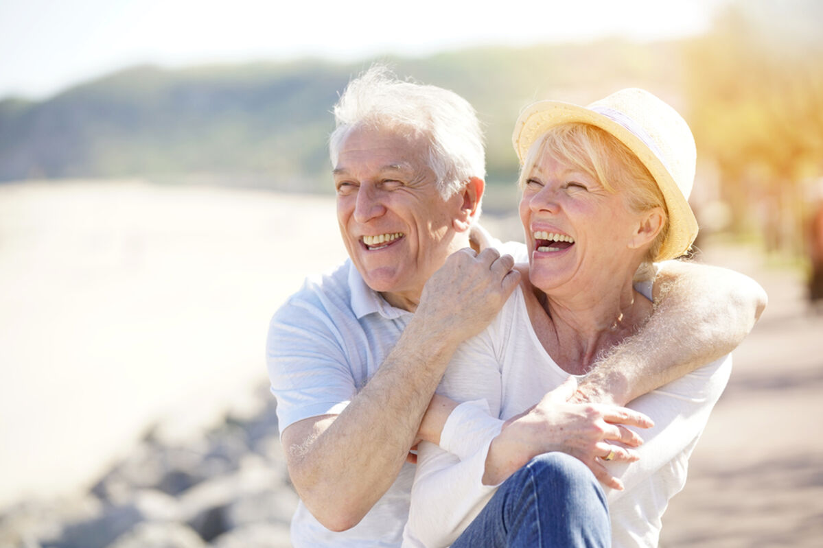 Older couple laughing in retirement on the beach 